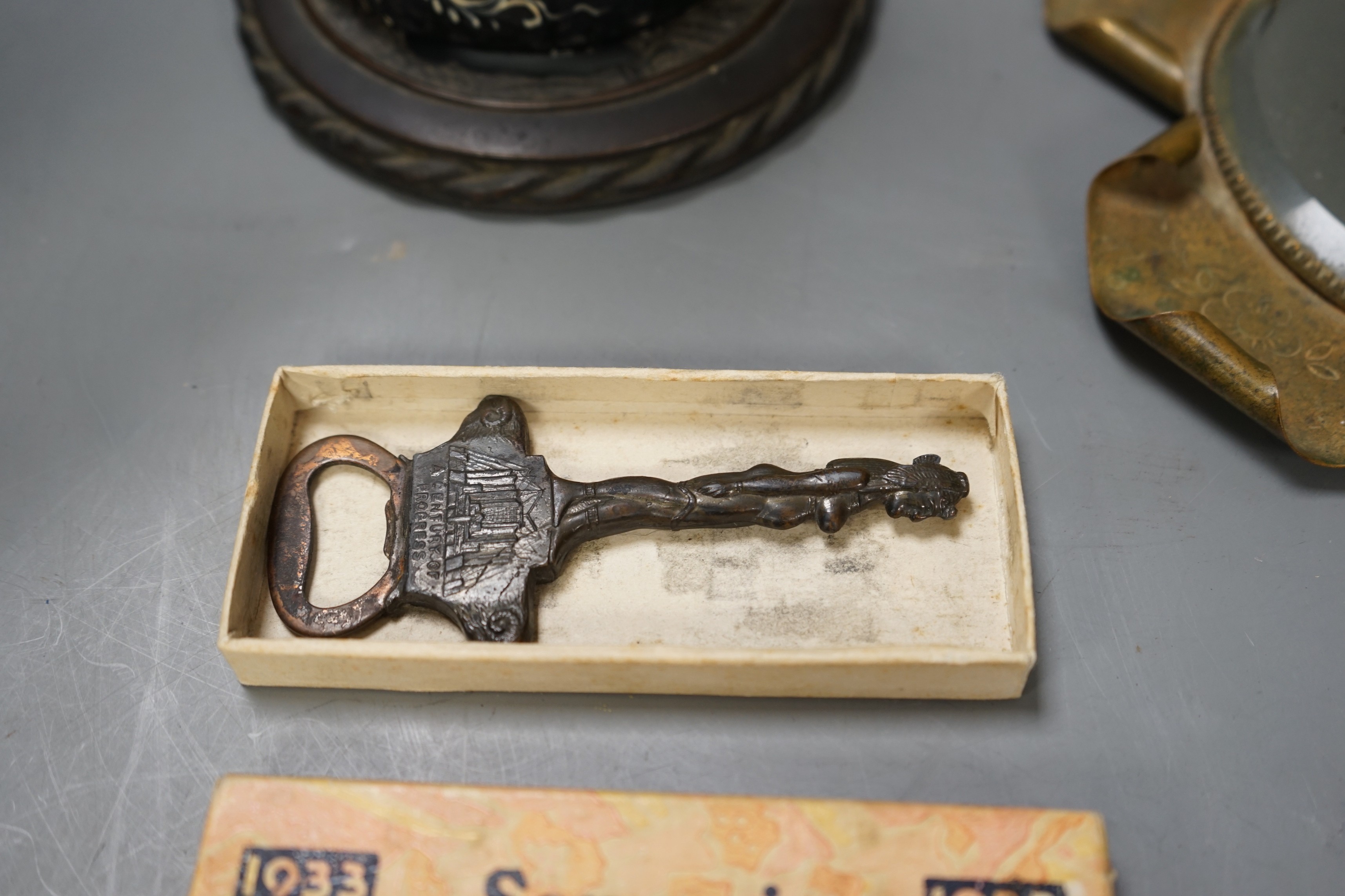 An Oriental carved painted wooden figure, together with an early 20th century 'Chicago World Fair' bottle opener souvenir, and a 1900 Paris exposition mirror with floral and scroll motif (3)